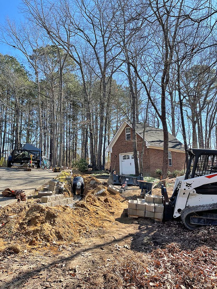 A bulldozer is digging a hole in the dirt in front of a house.