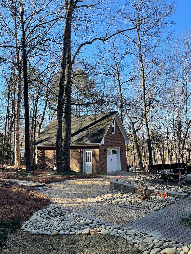 A small brick house in the middle of a forest surrounded by trees.