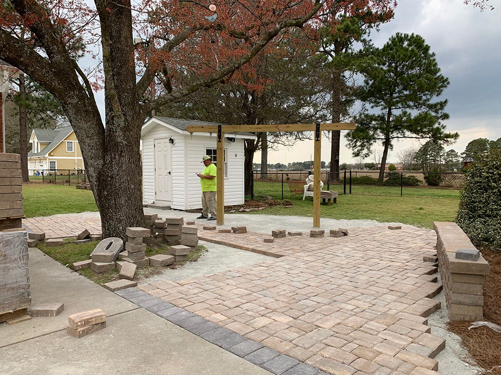 A man is standing in front of a shed in a backyard.