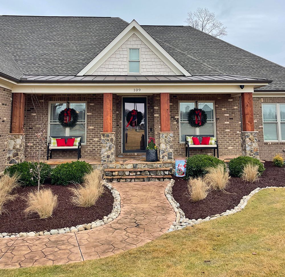 A brick house with a porch decorated for christmas