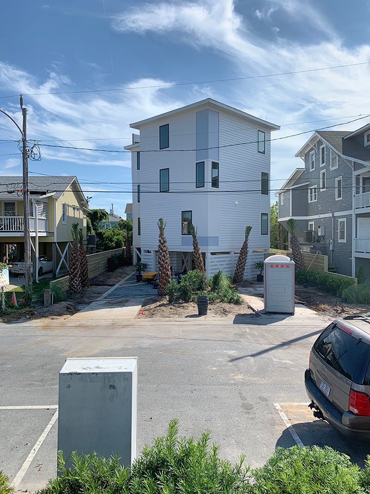 A car is parked in front of a large white house.