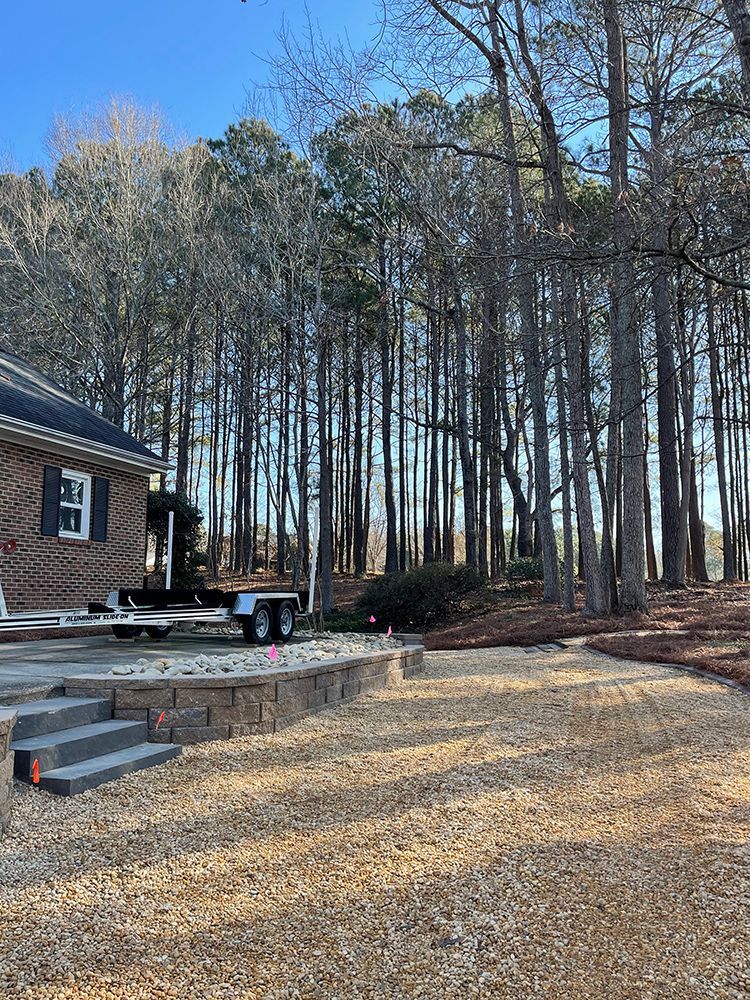 A house with a trailer parked in front of it in the woods.