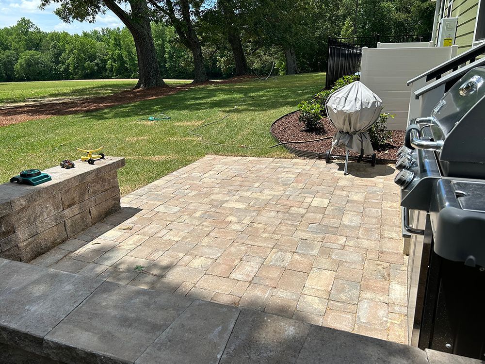 A patio with a grill and a bench in the backyard.