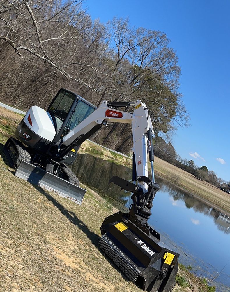 A small excavator is parked next to a body of water.