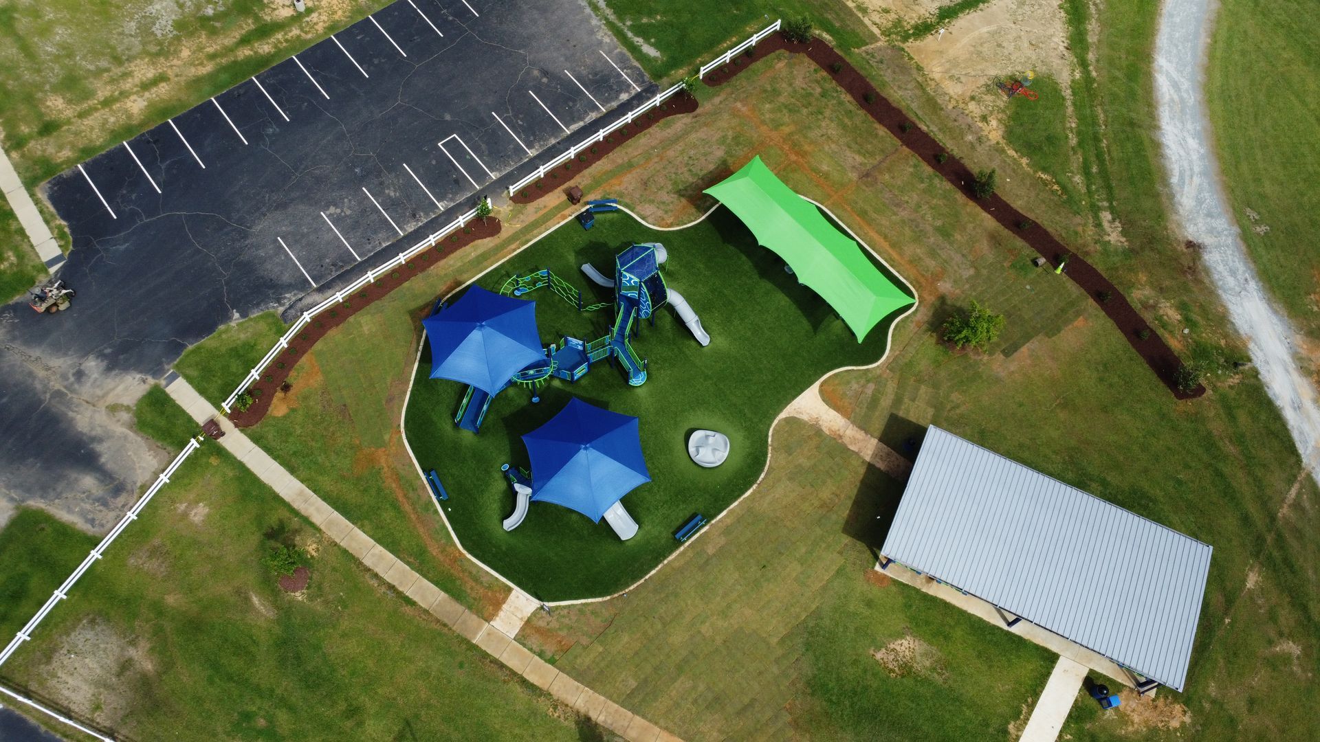 An aerial view of a playground with blue and green umbrellas.