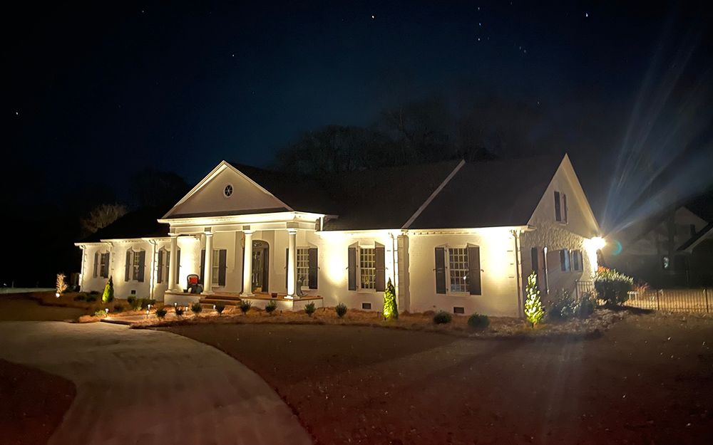 A large white house is lit up at night.