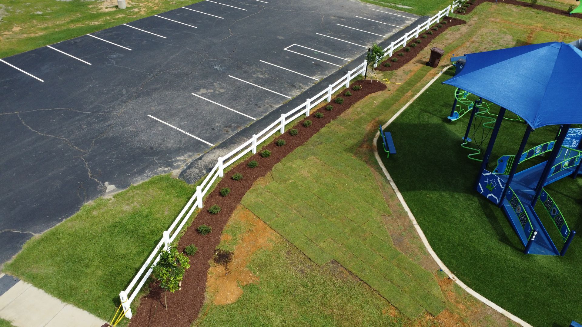 An aerial view of a park with a playground and a parking lot.