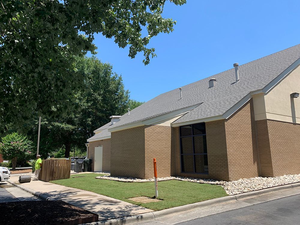 A brick building with a gray roof and a lawn in front of it.