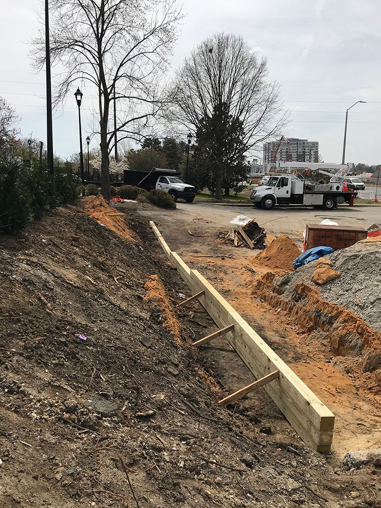 A wooden fence is being built on the side of a dirt road.