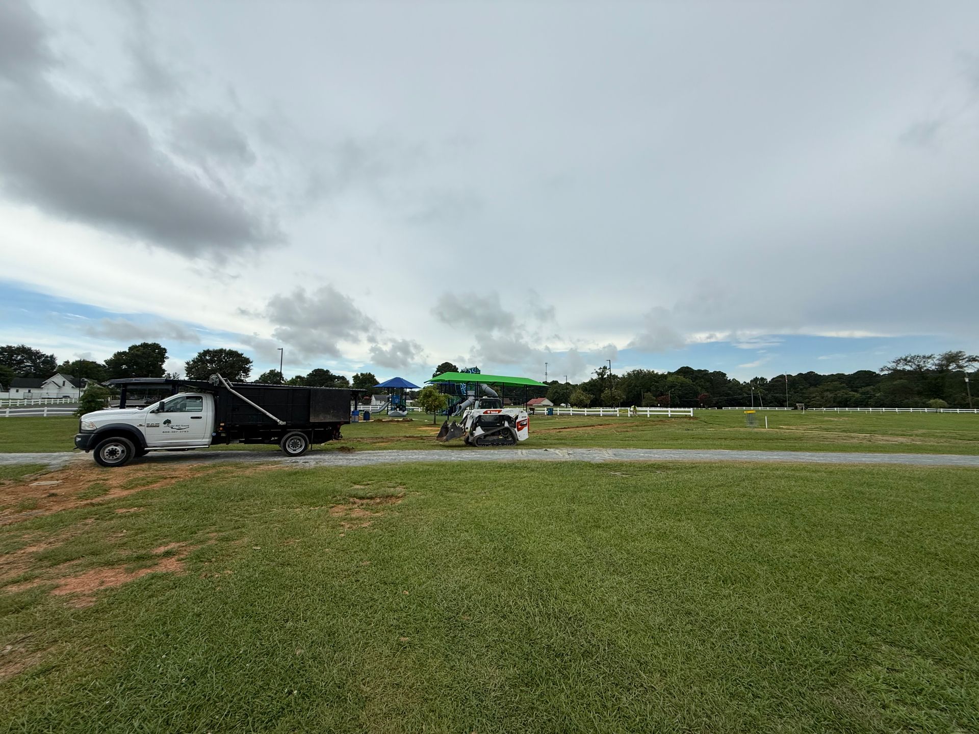 A white truck is parked in a grassy field next to a golf cart.