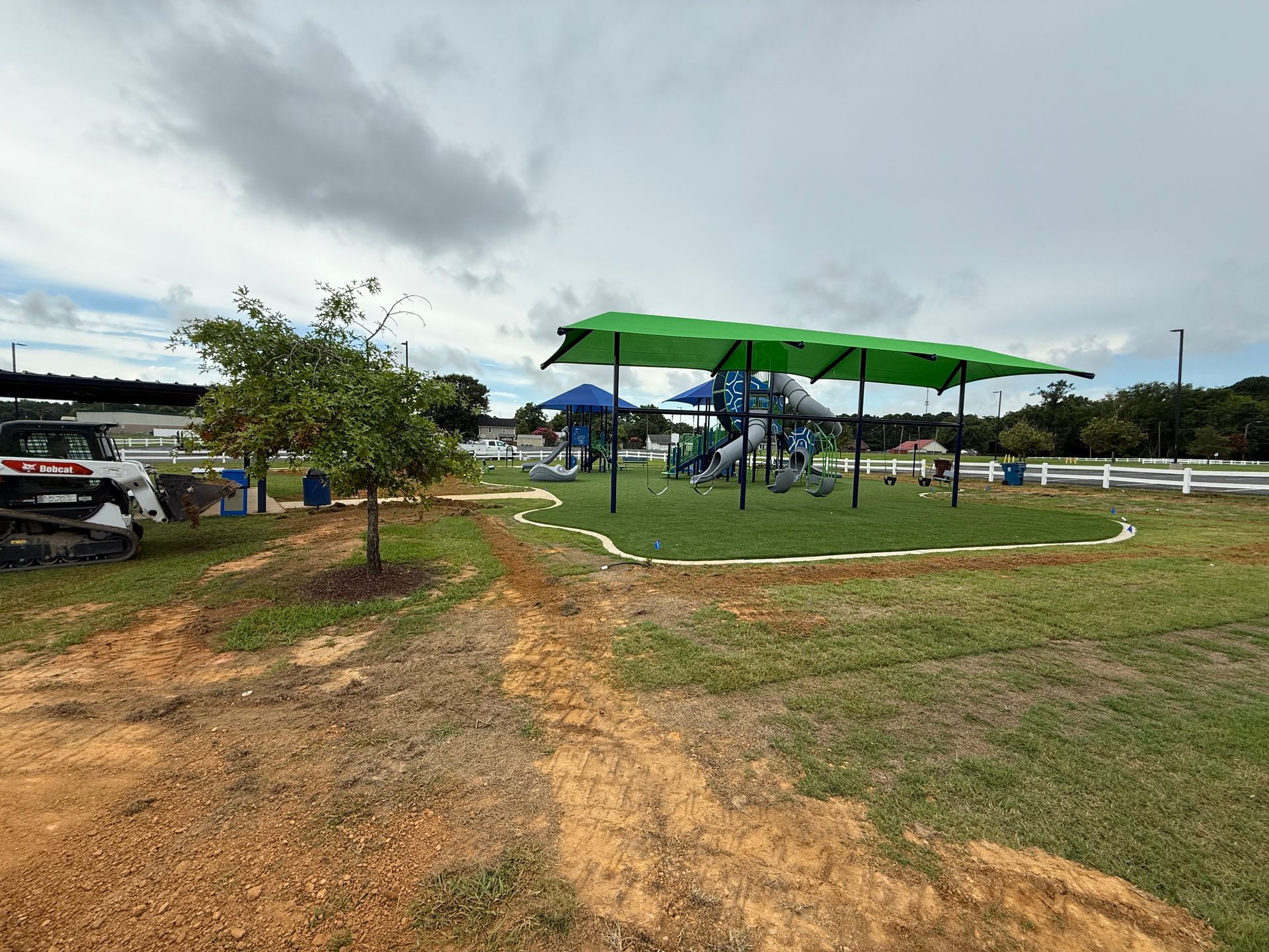 A playground is being built in a field with a green umbrella.