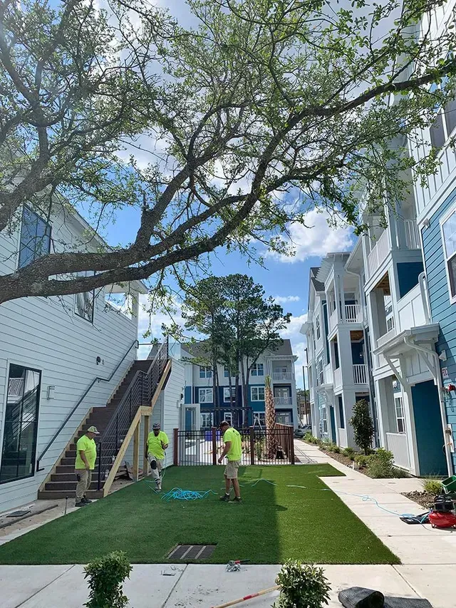 A group of people are working on a lawn in front of a building.