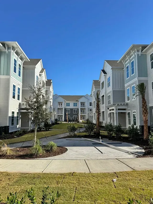 A large apartment building with a lot of windows and a lot of grass in front of it.