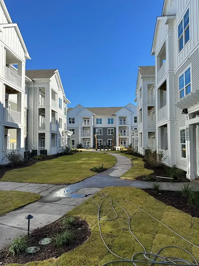 A large white apartment building with a walkway leading to it.