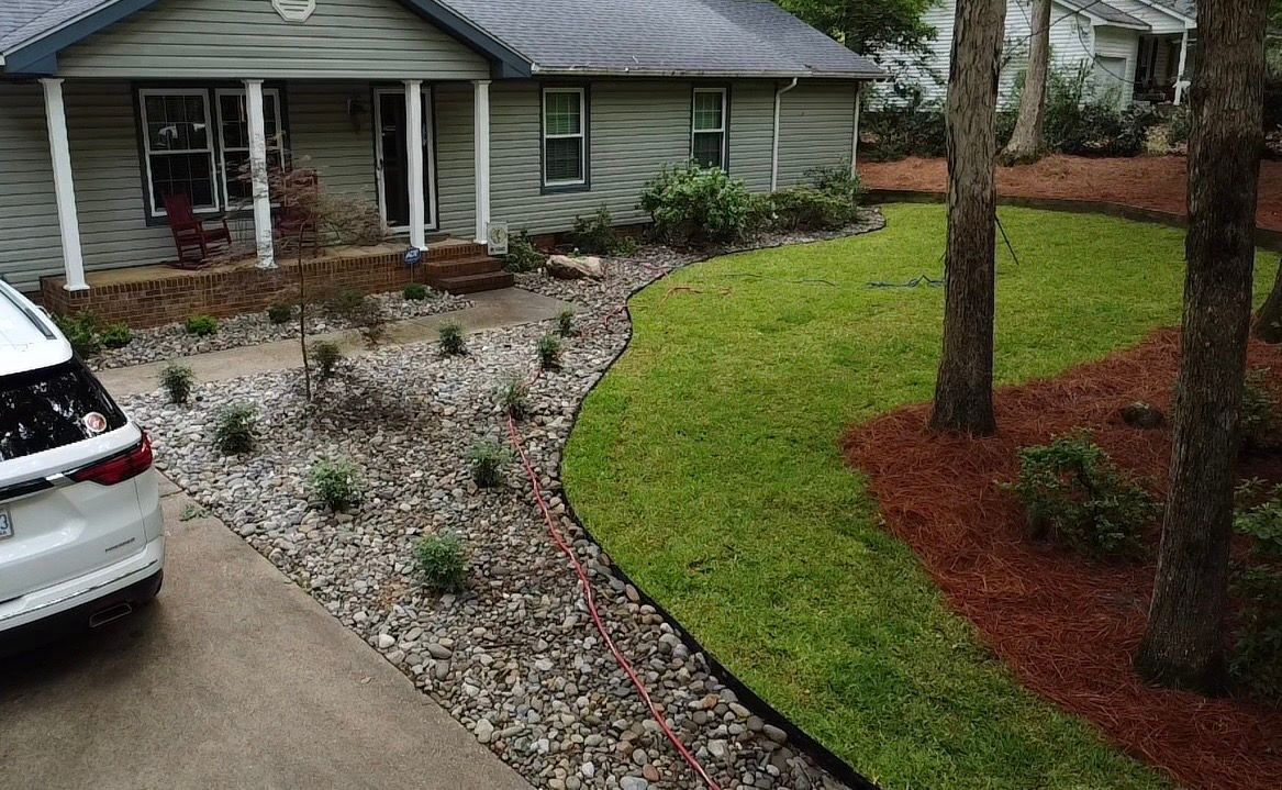 A car is parked in front of a house with a lush green lawn.