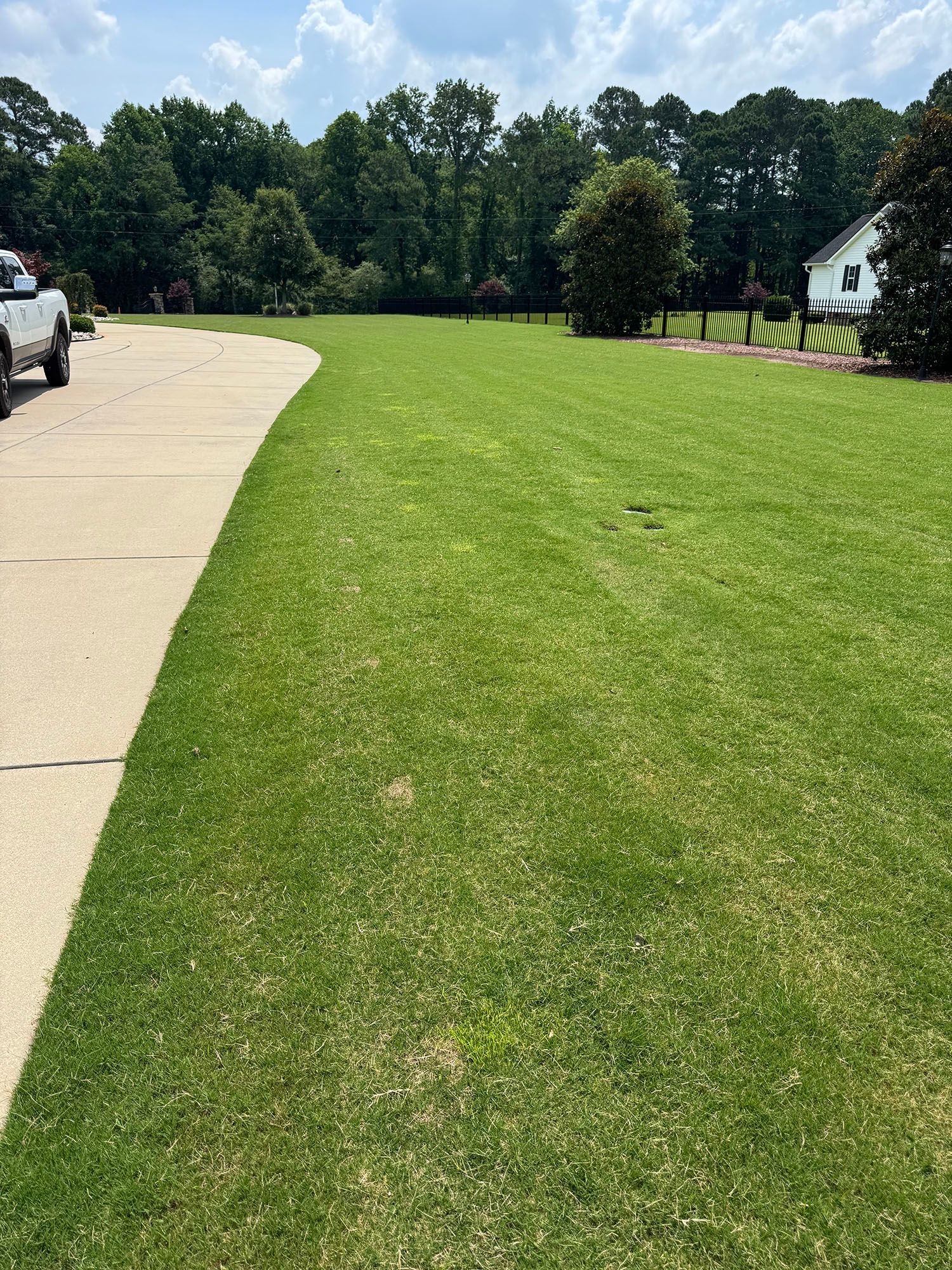 A car is parked on the side of a road next to a lush green field.