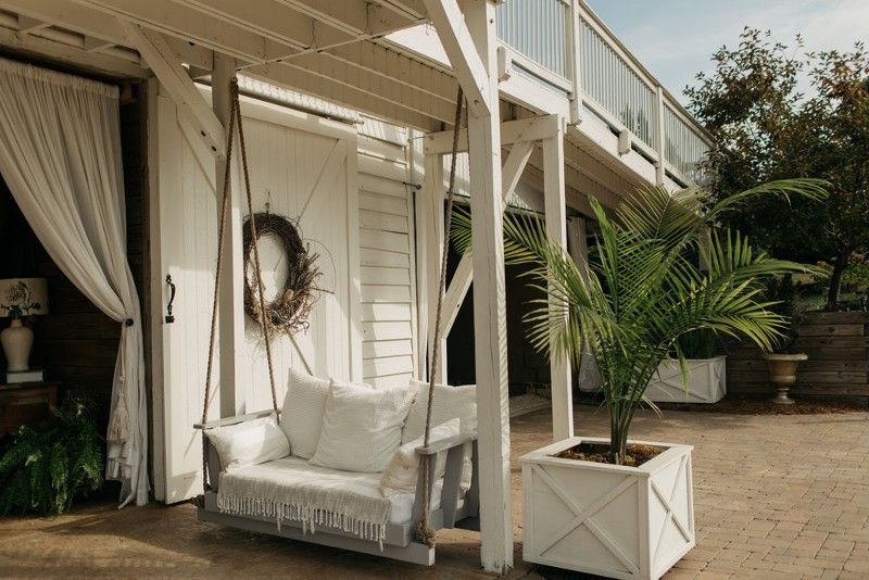 A porch with a swing and a palm tree.