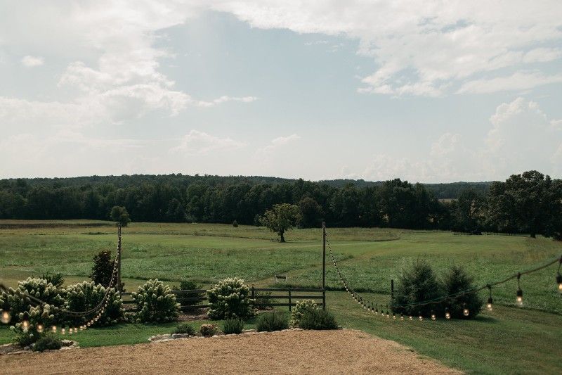A large grassy field with trees in the background and a fence in the foreground.