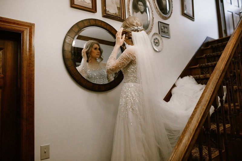 A bride is standing on a staircase looking at herself in a mirror.