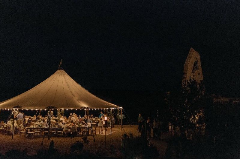 A group of people are gathered under a tent at night