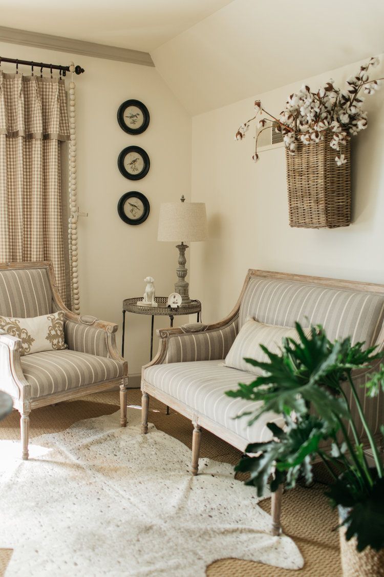 A living room with a couch , chairs , lamps and a plant.