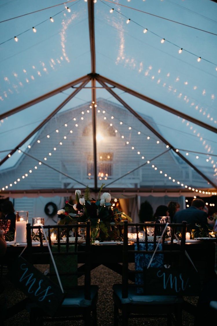 A group of people are sitting at tables under a tent.
