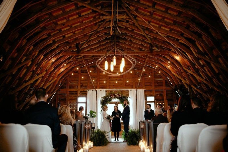 A bride and groom are getting married in a barn.