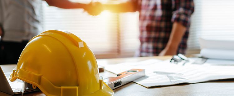 a yellow hard hat is sitting on a table next to a group of people shaking hands .