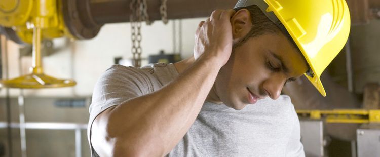 a man wearing a hard hat is holding his neck in pain .