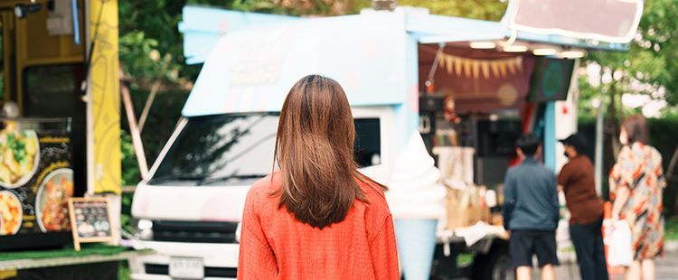 a woman is standing in front of a food truck .