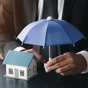 a man is holding an umbrella over a model house .