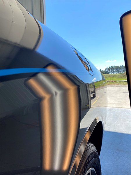 A black car with a dent in the fender