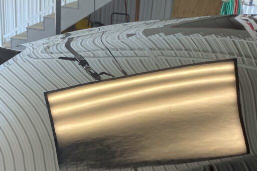 A car with a dent in the roof is sitting in a garage.