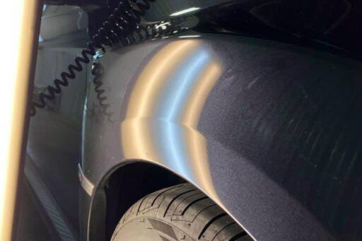A close up of a car fender with a cord attached to it.