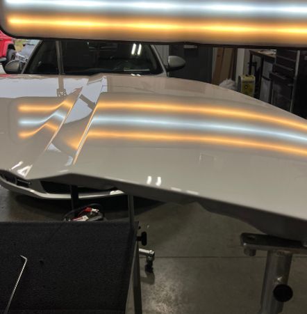 A silver car with a hood that has been dented