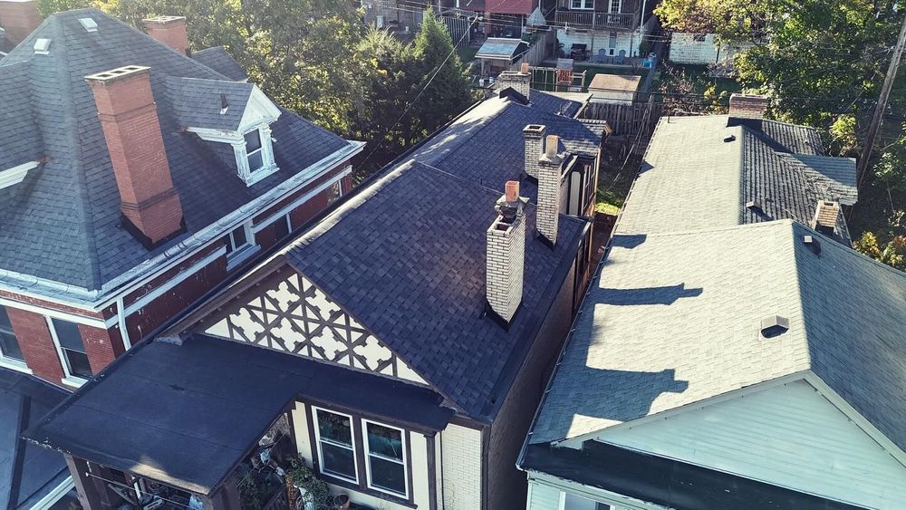 Roofs of several houses, viewed from above, with chimneys and a distinctive black and white gable.