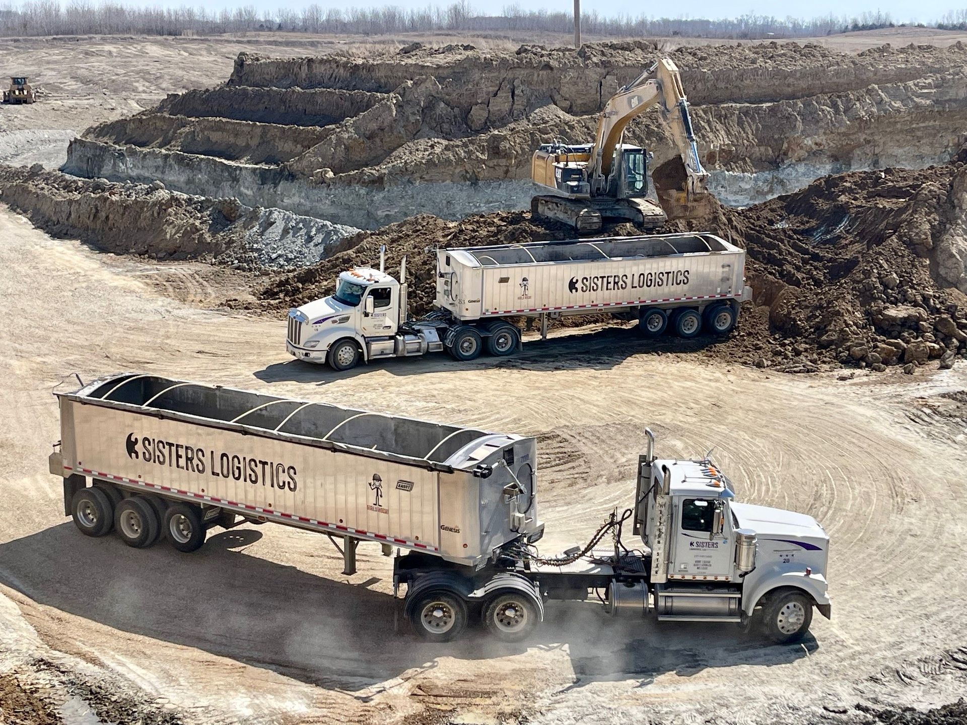 Dump trucks and excavator working in a muddy quarry excavation site