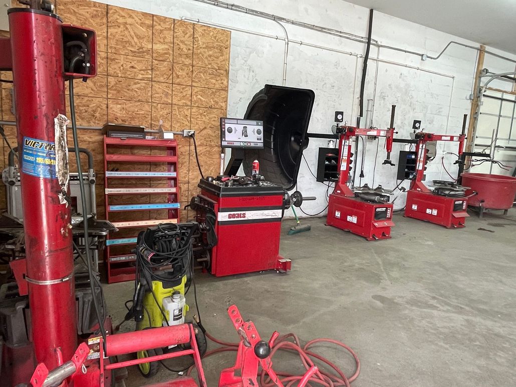 An automotive shop with red tire changing and balancing equipment arranged in a line against a wall.