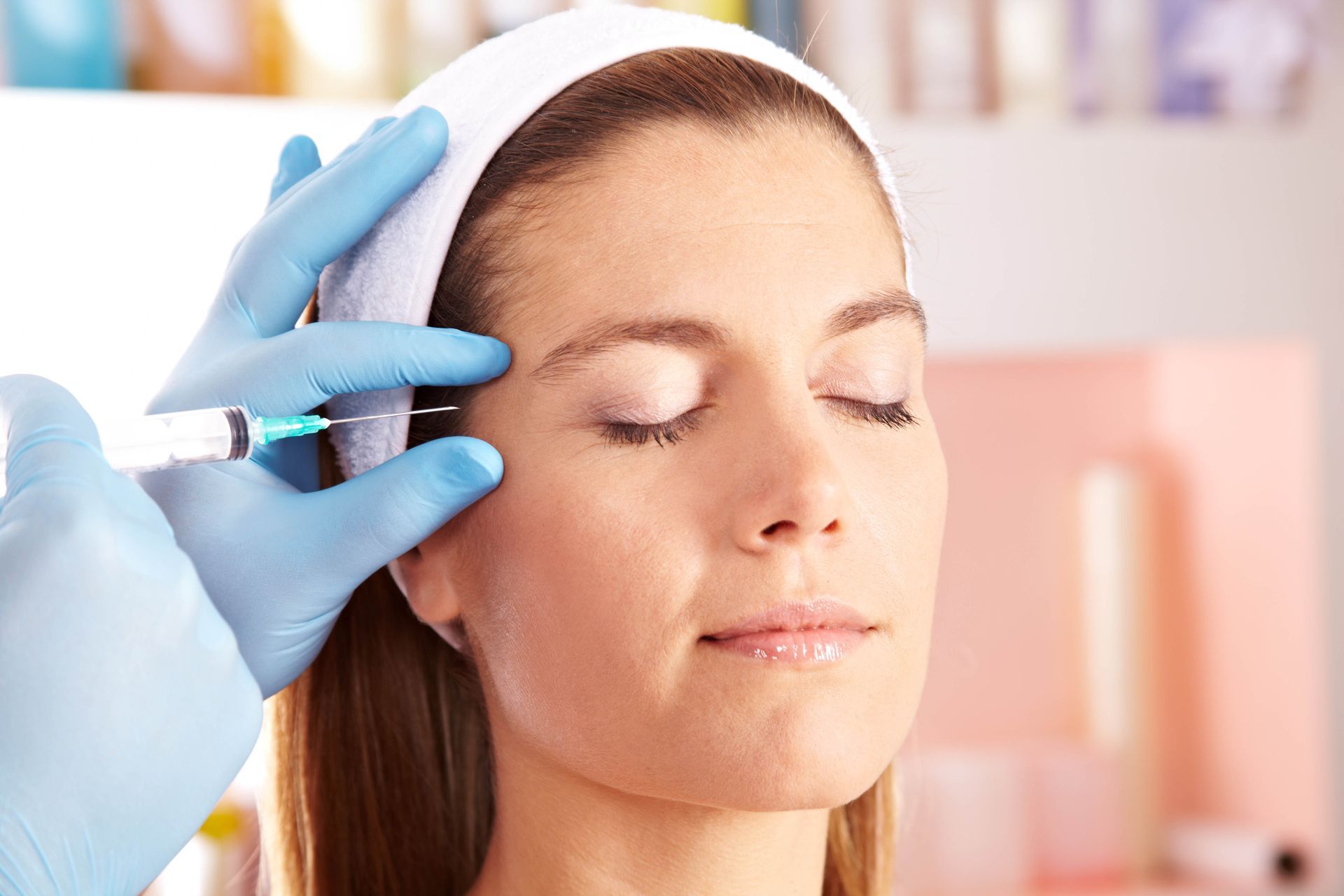 A woman is getting a botox injection in her forehead.