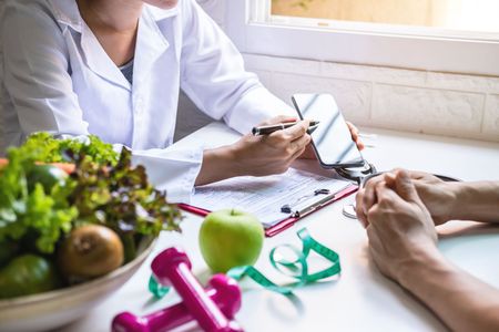 A nutritionist is talking to a patient at a table.