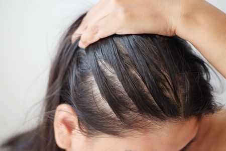 A woman is touching her hair with her hand.