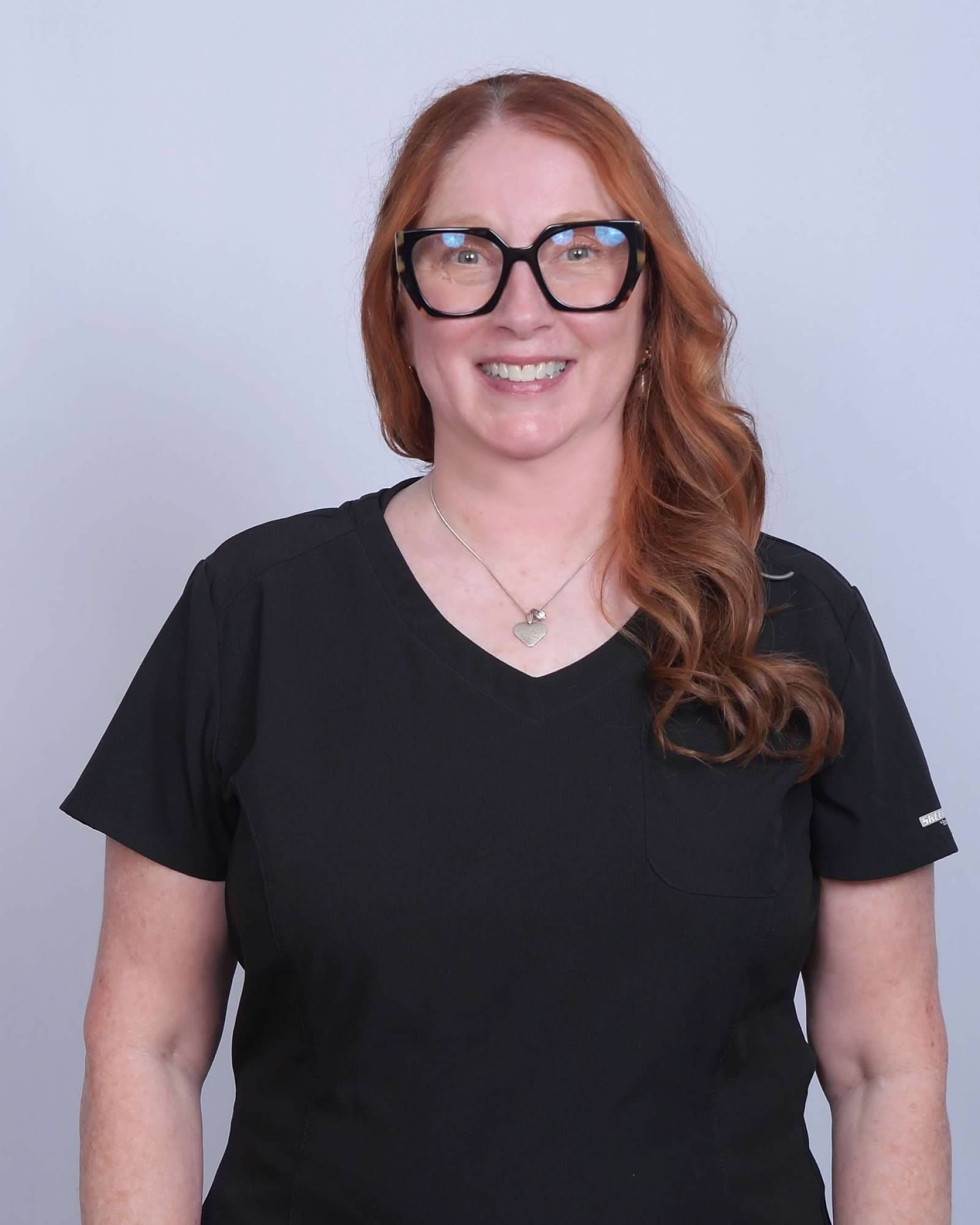 Woman with glasses smiling.