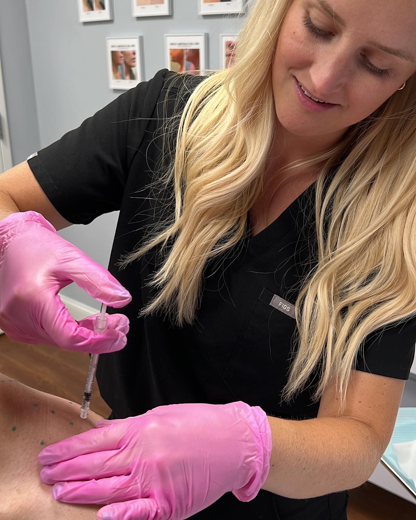 A woman wearing pink gloves is giving an injection to a patient.
