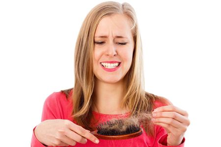 A woman is touching her hair with her hand.