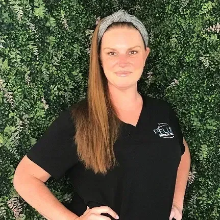 A woman wearing a headband and a black shirt is standing in front of a green wall.