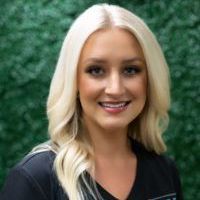 A woman with blonde hair is smiling and wearing a black shirt.