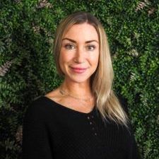 A woman in a black shirt is standing in front of a green wall.