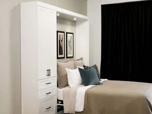 A bedroom with a bed and a wardrobe behind it.