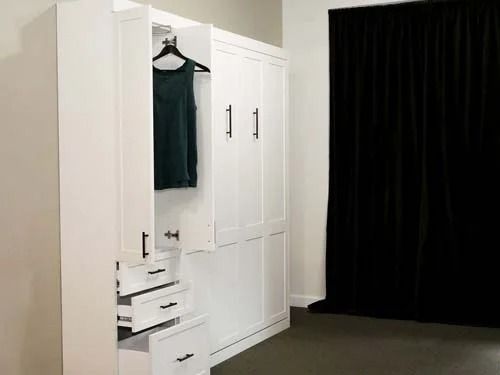 A white wardrobe with a green shirt hanging in it.