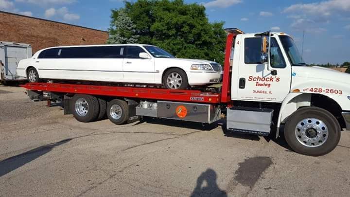 A tow truck with a limousine on the back of it.